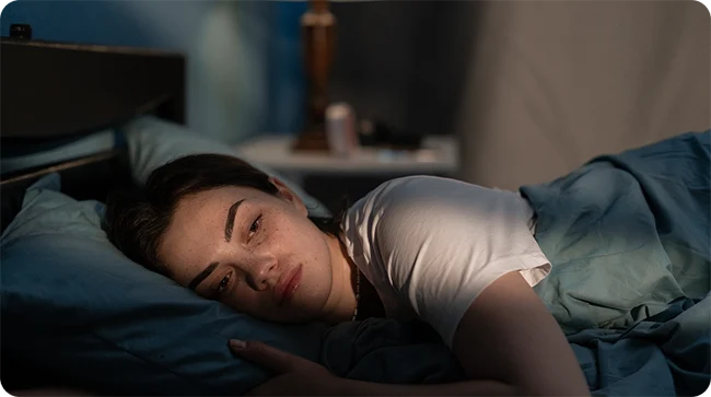 Woman lying awake in bed in a dim room