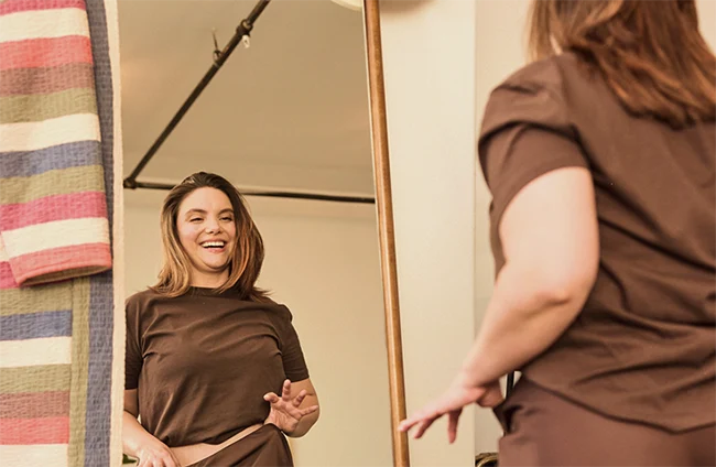 Smiling woman checking her fit in a mirror