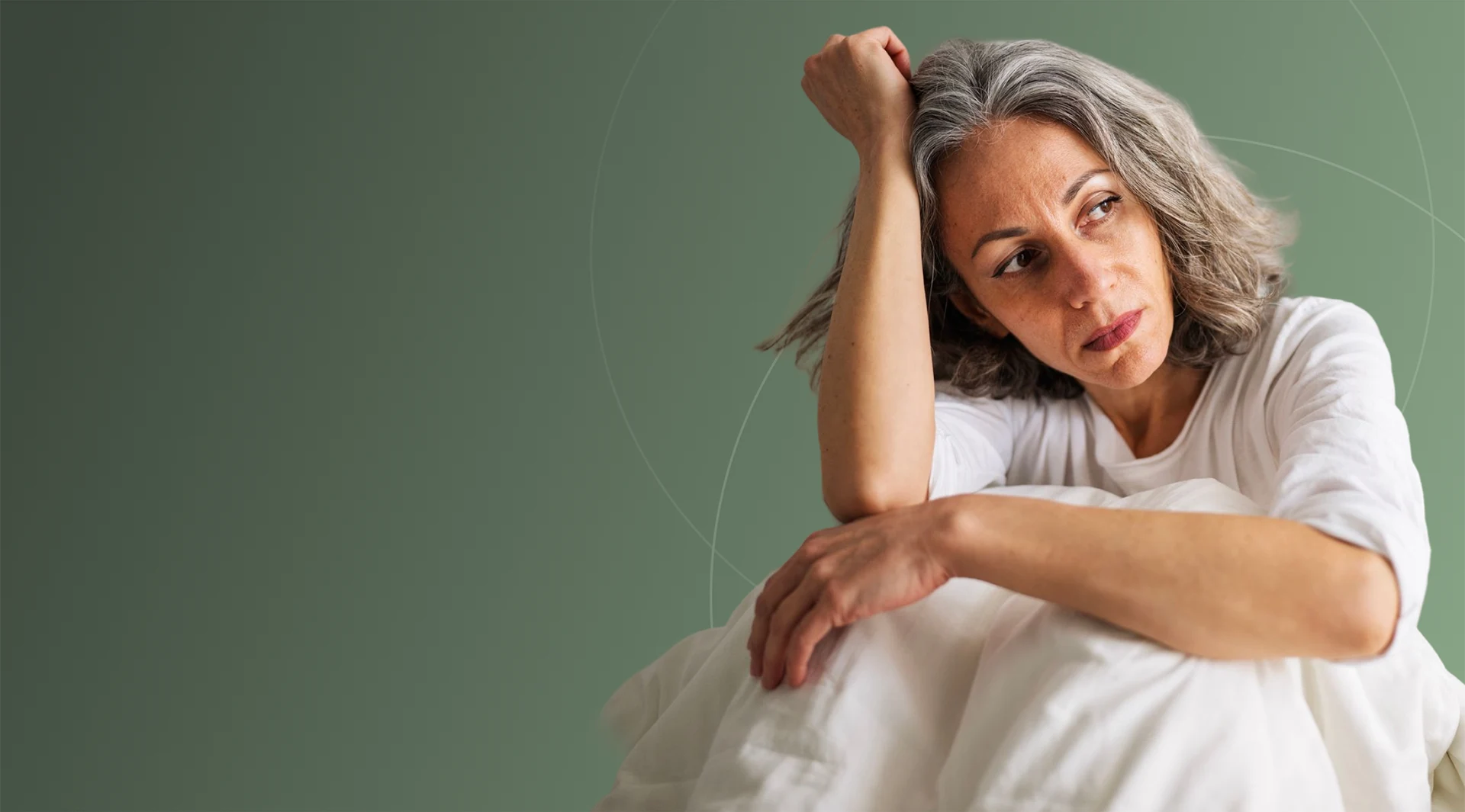 Woman sitting up in bed, resting her head on her hand
